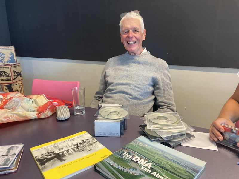 Kleurenfoto met Brans Stassen met op tafel cassettebandjes en cdroms met interviews